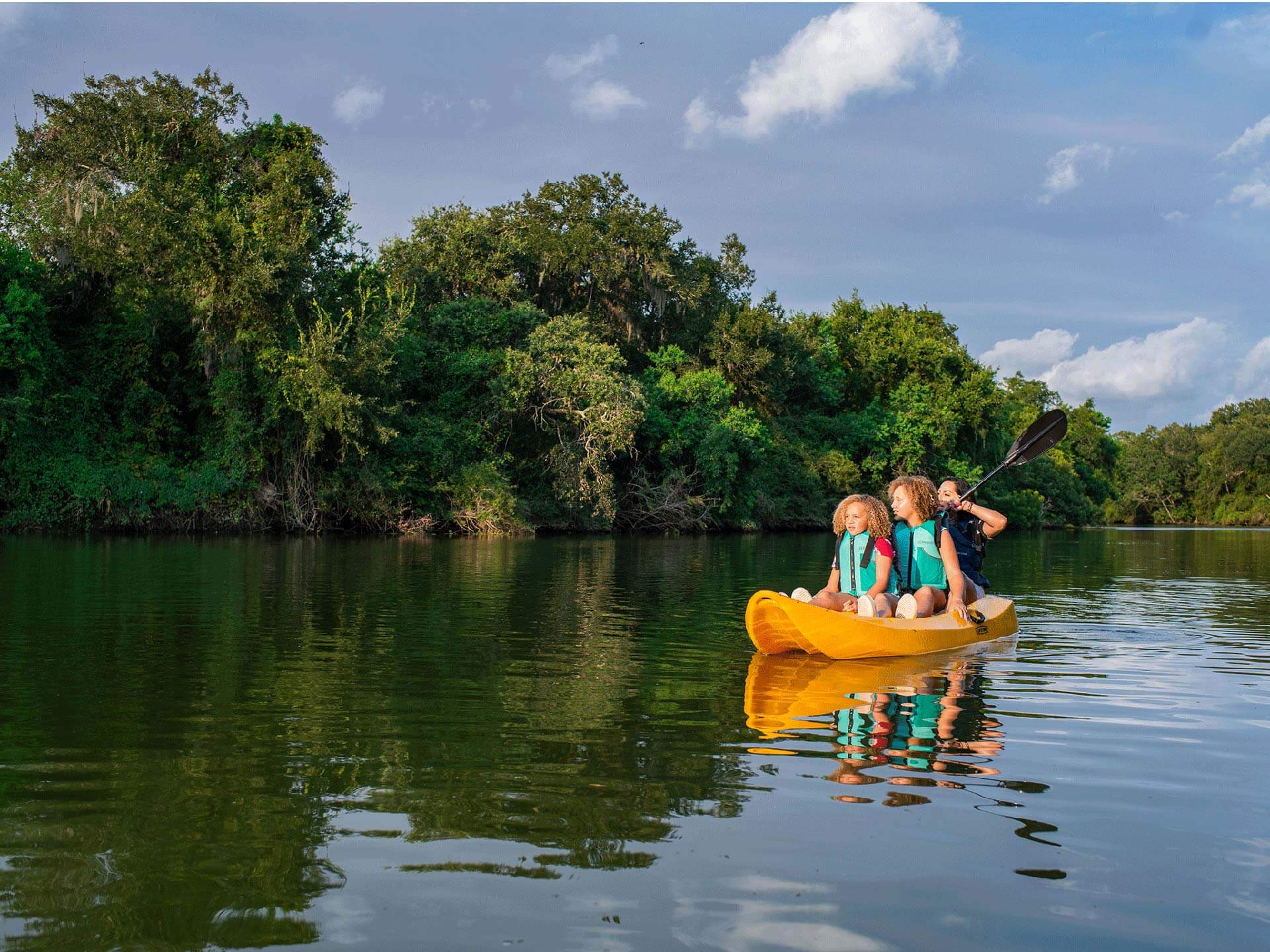 A family paddling a boat on a lake near Bay Area Houston