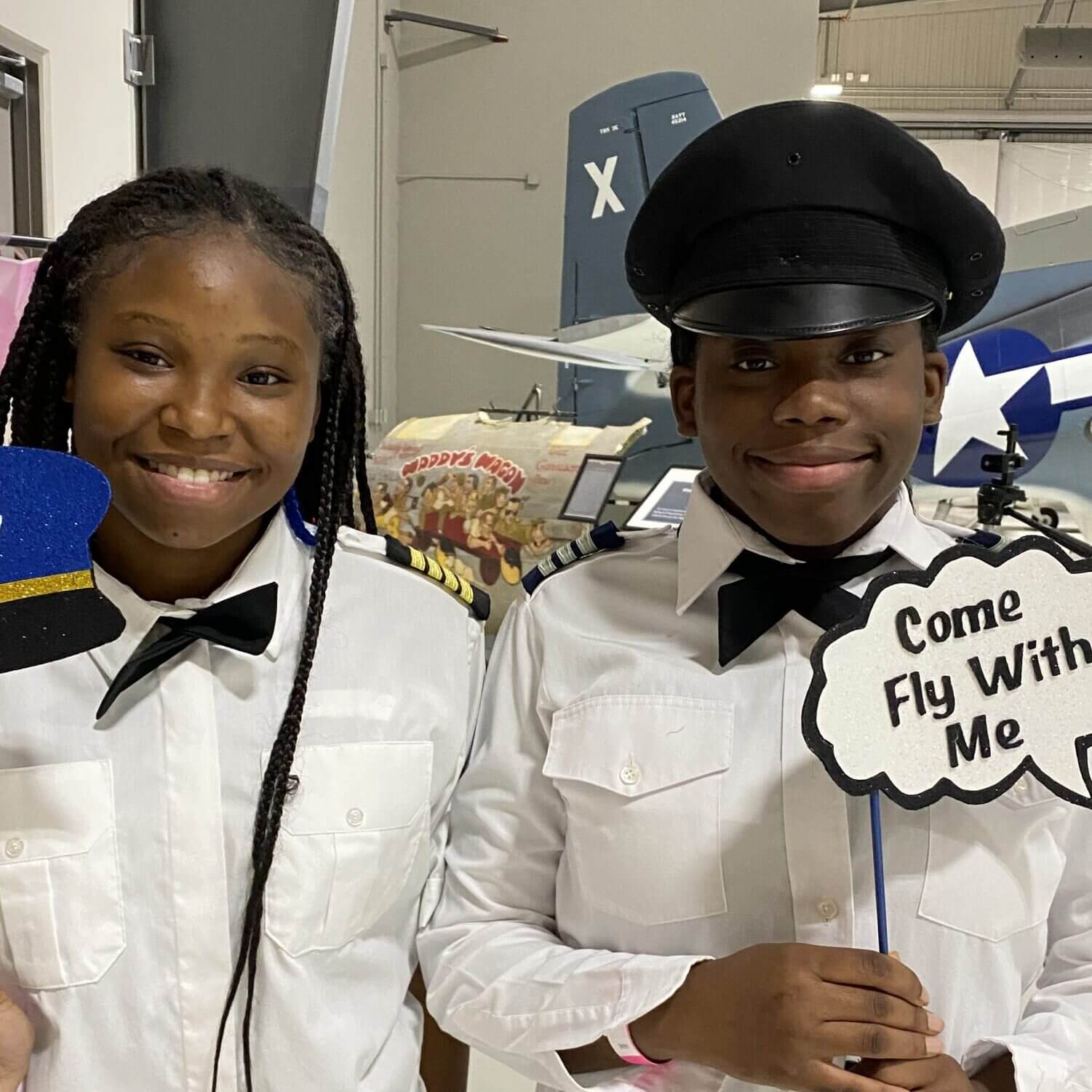 Two girls smile as they dress up like pilots during a girl's summer camp program hosted at the Lone Star Flight Museum in Houston, TX.