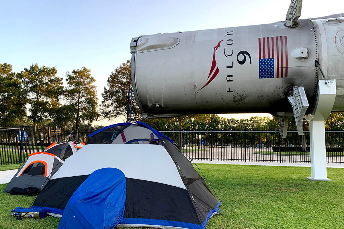A tent is pitched beside one of the space vessels featured on the grounds of Space Center Houston during a family overnight camping experience.