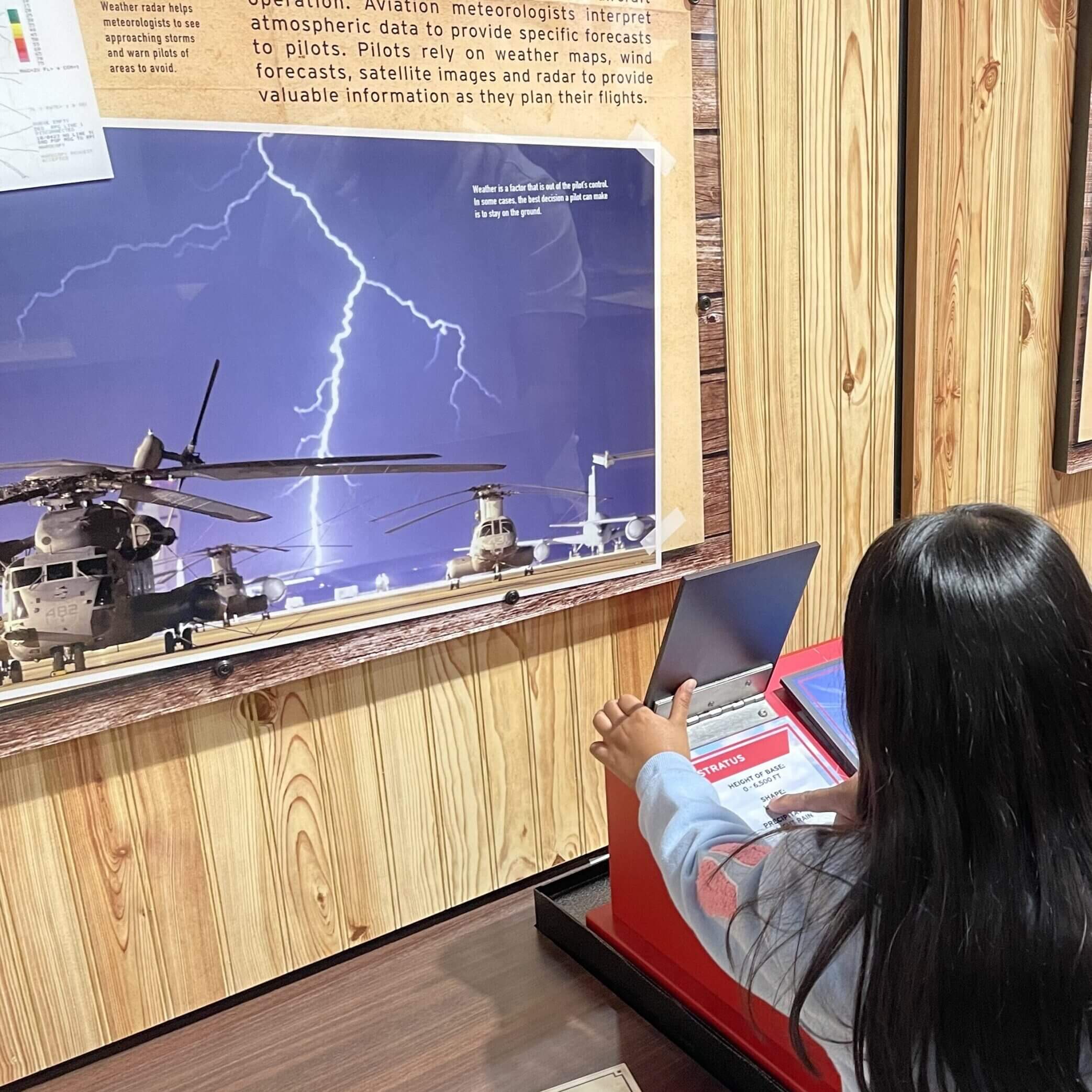A girl tests her knowledge of weather patterns during one of the summer camp programs hosted at the Lone Star Flight Museum in Houston, TX.